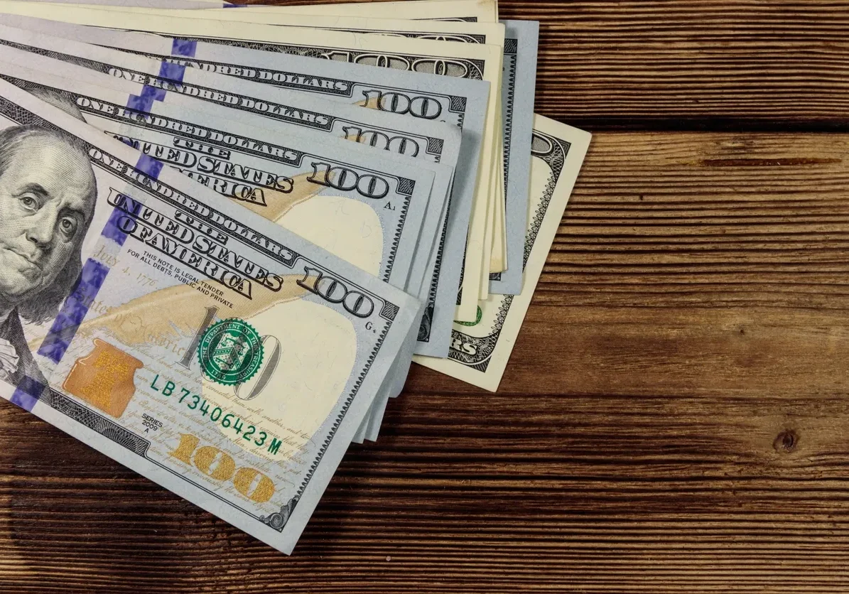 Pile of US currency on wood surface